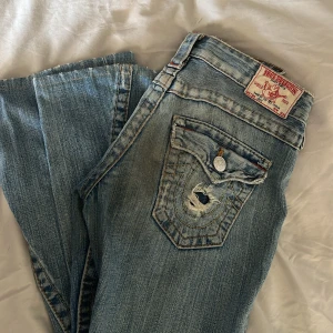 True Religion Joey jeans bootcut blå - Säljer nu mina absoluta favorit jeans då jag tyvärr måste inse att dom blivit alldeles för små för mig 🩶 Vintage True Religion jeans i bootcut modellen ”Joey” med väldigt låg midja och ljusblå tvätt. Storlek w25, passar bra i längden på mig som är 166cm. OBS: hålet vid knät har töjts ut lite sedan fjärde bilden togs, men bara något som gjort jeansen snyggare enligt mig 🫶🏻