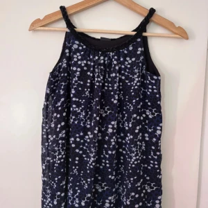 Topp - Mörkblå topp med svarta och vita prickar. Har en avslappnad och kort passform.