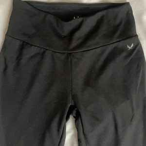 Svarta lågmidjade träningsbyxor från SOC - Snygga svarta träningsbyxor från SOC med låg  midja och bootcut-stil. Perfekta för både gymmet och avslappnade dagar. Tillverkade i ett mjukt och stretchigt material för optimal komfort.