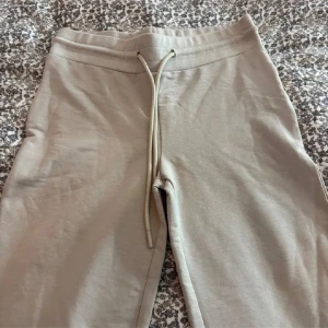 Beige Ebba low waist mjukisbyxor - Säljer ett par beige mjukisbyxor från Lager 157 med låg midja och bootcut passform. Byxorna har snörning i midjan och är gjorda i mjukt bomullsmaterial. Säljer då de ej kommer till användning längre💞