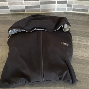 Hugo Boss hoodie  - Svart hoodie från Hugo Boss i storlek M med grått foder i huvan och snyggt broderad logga på bröstet. Tröjan har hel dragkedja framtill , skriv vid intresse 