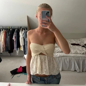 Beige bandeau tubtopp med spets från Zara - Säljer en superfin bandeau tubtopp i beige med virkad överdel och spetsdetaljer nedtill. Toppen är axelbandslös och har en snygg omlott-twist framtill samt broderade blommor i spetsen. Perfekt till både jeans, shorts och kjol!🌸💕