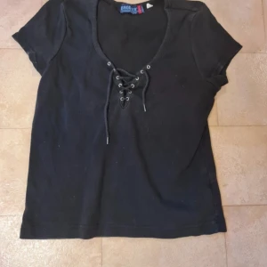 Svart t-shirt med snörning - Säljer en en kompis tshirt med snöre detalj. Storlek L men är ganska liten i storlek men den är stretchig😊