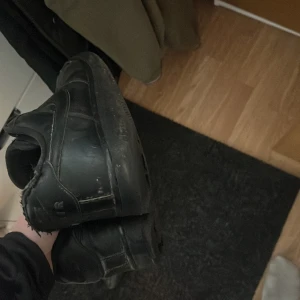 Svarta sneakers - Säljer ett par svarta sneakers med snörning. De har en klassisk design och är perfekta för vardagsbruk. Skorna är tillverkade i syntetmaterial och har en normal passform.