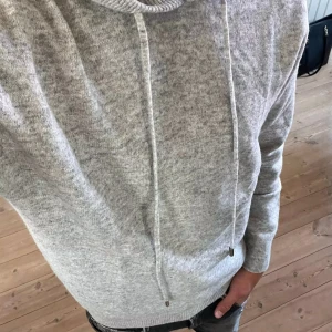 Grå hoodie - Säljer en stilren grå hoodie med dragsko i huvan. Perfekt för en avslappnad look. Tröjan har långa ärmar och ribbade muddar vid ärmslut och nederkant. Använd endast 1 gång, väldigt bra pris!