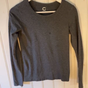Grå långärmad tröja  - Säljer en stilren grå långärmad tröja från C i ekologisk bomull. Perfekt för en avslappnad look. Tröjan har en rund halsringning och är i en mjuk och bekväm kvalitet.