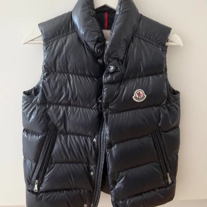 Mörkblå dunväst från Moncler - Säljer nu min Moncler väst i mörkblått som inte kommer till användning. Använd max 10 ggr. Är i storlek 152 cm men passar mig som är XS/S. Köpt för 4 920 kr på Miinto 