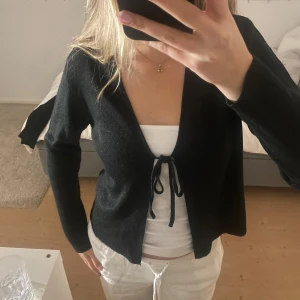 Svart glittrig kofta - Säljer en svart glittrig kofta med knytning framtill. Koftan har långa ärmar och är perfekt för att lägga till lite extra till outfiten🎀👛
