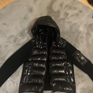 Moncler Cardigan - Snygg svart cardigan från Moncler. Säljs pågrund av att den var för liten när jag köpte den. Bra skick, inga skador. Har ej kvitto därför låga priset. Bara att skriva om du har några mer fråger!