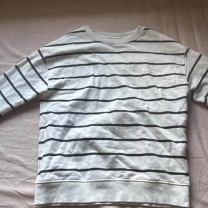 Vit och svart randig tröja från Zara - Säljer en vit och svart randig tröja från Zara i storlek 140. Tröjan har långa ärmar och är perfekt för en avslappnad stil. Den är gjord i ett mjukt material som känns skönt mot huden.