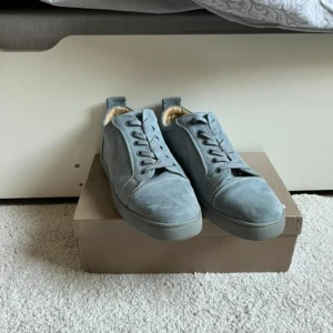 Grå sneakers från Christian Louboutin - Snygga grå sneakers i mocka från Christian Louboutin med den ikoniska röda sulan. Skorna har snörning och en stilren design som passar perfekt för en trendig look. (Knappast använd) 