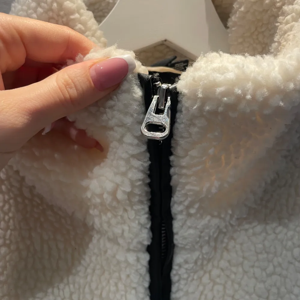 Oversized vit teddyjacka från Vero Moda med dragkedja framtill. Jackan har en hög krage och två praktiska fickor. Stl XS men sitter rent storleksmässigt som kanske M. Går nedanför rumpan på mig som är 172. Det är lite smink rester på kragen, ska ta bort det som går. . Takit.