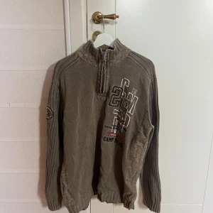 Grön tröja  - Säljer en grön tröja från Camp David med tryck på både fram- och baksidan. Tröjan har långa ärmar och en hög krage med dragkedja. Köpt vintage så den är använd men inget sönder eller annat, fint skick!