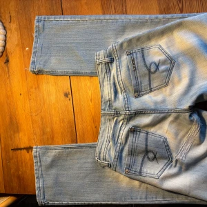 Ljusblå jeans med slitna detaljer - Snygga ljusblå jeans från Replay med slitna detaljer vid benslut och bakfickor. Jeansen har en klassisk femficksdesign och en knappgylf. Perfekta för en avslappnad stil. Har behövt sy ihop de för de spräckts men ingenting som syns så tydligen när jeansen är på