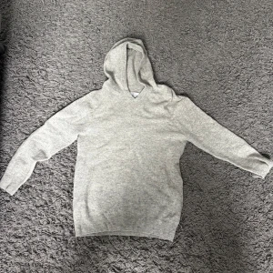 Grå hoodie - Säljer en stilren grå hoodie med långa ärmar och ribbade muddar. Köpt från gardegrisch. Hör av dig vid intresse! 