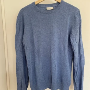 Blå tröja från Lindbergh - Säljer en stilren blå tröja från Lindbergh. Tröjan har en klassisk rund halsringning och långa ärmar. Perfekt för en avslappnad look. Passar bra till både jeans och chinos. Den har några små tvätthål, se bilderna