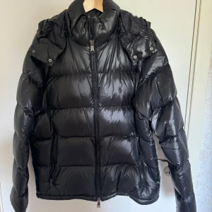 polo ralph lauren jacka - Säljer en svart pufferjacka med dragkedja och huva. Jackan har en glansig yta och långa ärmar, perfekt för kyliga dagar. Den är stilren och enkel att matcha med olika outfits.