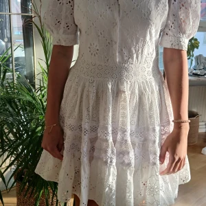 Maje klänning strl 38 - Säljer en superfin vit klänning med spetsdetaljer och kort ärm. Klänningen har en v-ringad design och en öppen rygg som ger en extra touch. Perfekt för sommarens alla tillfällen! 💫            Fint skick