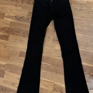 Svarta bootcut jeans från Hollister - Snygga svarta bootcut jeans från Hollister med midwaist passform. Jeansen har klassisk design med fem fickor och en knappgylf. Perfekta för en stilren look. Storlek w23R. 