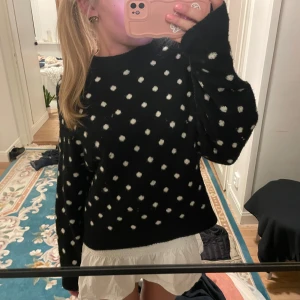 Svart prickig tröja - Säljer en svart tröja med vita prickar. Tröjan har långa ärmar och en normal passform. Perfekt för en stilren och lekfull look.