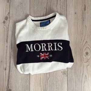 Tröja från Morris - Säljer en stilren vit tröja från Morris med blå och broderad logga samt brittisk flagga framtill. Tröjan har ribbade muddar vid ärmslut och nederkant. Perfekt för en nice look och perfekt till Våren. Kan gå ner i pris vid snabb affär!
