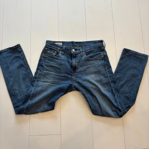 Blå jeans 502 från Levi's - Klassiska blå jeans från Levi's med rak passform. De har en knappgylf och femficksdesign. Perfekta för en avslappnad stil. Med en liten sked på byxbenet 