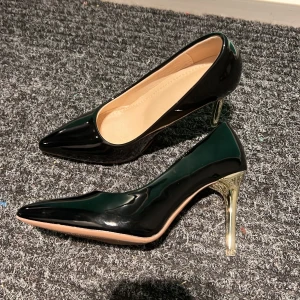 Svarta pumps med gulddetaljer - Eleganta svarta pumps med spetsig tå och glänsande guldfärgade klackar. Perfekta för att ge en lyxig touch till din outfit.