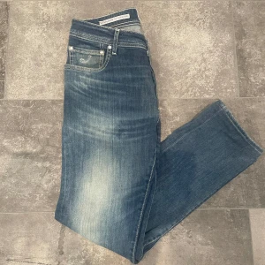 Jacob cohen jeans - Jeans från Jacob Cohën med en klassisk femficksdesign och knappgylf. Jeansen har en diskret tvättad look och en läderpatch med logotyp på baksidan. Tveka inte på att kontakta mig vid fler frågor eller funderingar.