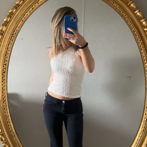 Vit oneshoulder topp - Säljer en snygg vit oneshoulder topp med en texturerad yta. Aldrig använt