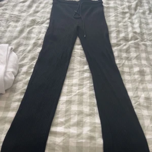 Svarta ribbade byxor - Snygga svarta ribbade byxor med snörning i midjan. Perfekta för en avslappnad stil och kan enkelt matchas med olika toppar. Byxorna har en tight passform och är tillverkade i ett mjukt material för extra komfort.