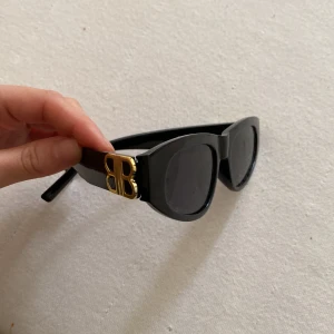 Svarta solglasögon med gulddetaljer - Snygga svarta solglasögon med rektangulära linser och coola gulddetaljer på sidorna. Perfekta för att ge din outfit en extra touch av stil. Passar bra till både vardag och speciella tillfällen.