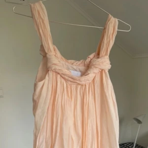 Ljus persikofärgad klänning - Charmig ljus persikofärgad klänning med breda axelband och en mjukt draperad design. Perfekt för en somrig look med sin luftiga och bekväma passform! 