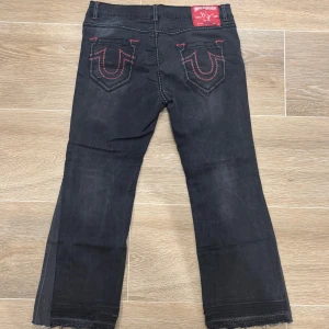 True Relgion Unisex jeans - Relativt sällsynta truies med röd/grå fat stich och svarta, var väldigt svåra att hitta, storlek 34 i kvinnostorlek antar jag, säljer dom pågrund av att jag har växt ut dom och får inte plats längre, som man ser har jag flarat dom längst nere för lite mer bootcut, tyckte det va snyggare än bara helt straight fit, älskar dessa så mycket men tyvärr dags att låta någon annan njuta av de, angåande äktenhet så har dom blivit verifierade som äkta av dom jag har kollat med men kan ej lova (skriv dm)