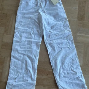 Vita linnebyxor från Gina Tricot Young - Säljer ett par vita linnebyxor från Gina Tricot Young. Byxorna har en avslappnad passform med resår i midjan och är tillverkade i ett linneblandat material för en luftig känsla. Perfekta för varma dagar! Helt oanvända, säljer dem för att de är för småa. 