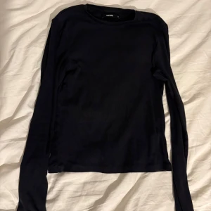 Svart långärmad tröja från bikbok - Säljer en stilren svart långärmad tröja från bikbok. Perfekt för lager-på-lager eller som den är. Tröjan har en enkel design med rund hals och är tillverkad i ett mjukt material.
