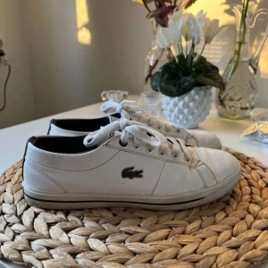 Vita sneakers från Lacoste - Snygga vita sneakers från Lacoste med klassisk design. Skorna har snörning och en diskret Lacoste-logga på sidan. Perfekta för en stilren look. Skicket är i mycket bra skick säljs pågrund av att de inte kommer till användning skriv vid frågor eller funderingar😊