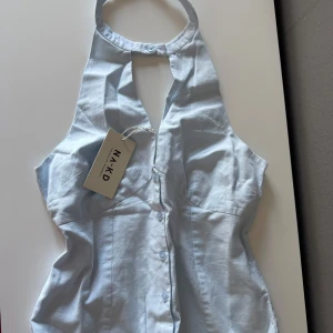 Topp från chloe schuttermans kollektion av NA-KD - Snygg ljusblå halterneck topp från Chloe Schuttermans kollektion av NA-KD med knappar framtill. Så fin!!