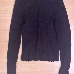 Svart ribbad tröja från Bershka - Säljer en stilren svart ribbad tröja från Bershka. Tröjan har långa ärmar och en bekväm passform som passar perfekt till vardags. Perfekt för lager-på-lager eller som den är.