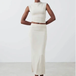 Beige set från Gina triccot  - Det beiga settet är bara använts en gång och är annars sprillans ny. Toppen är i storlek S och kjolen är i storlek M. Settet är perfekt för påsken eller för sommaren. 