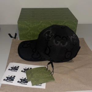  keps från Gucci Jumbo Svart - Snygg svart keps från Gucci med det ikoniska GG-mönstret. Kepsen har en justerbar rem baktill för perfekt passform. Perfekt för att ge din outfit en lyxig touch. Finns i S M L