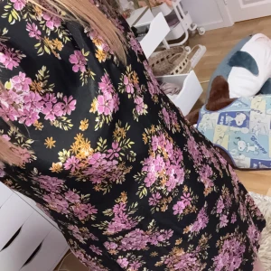 Svart blommig klänning💕💕 - Säljer en svart klänning från Love Label med vackert blommönster i rosa och gult. Klänningen har korta ärmar och en dragkedja bak. Perfekt för en färgglad look!
