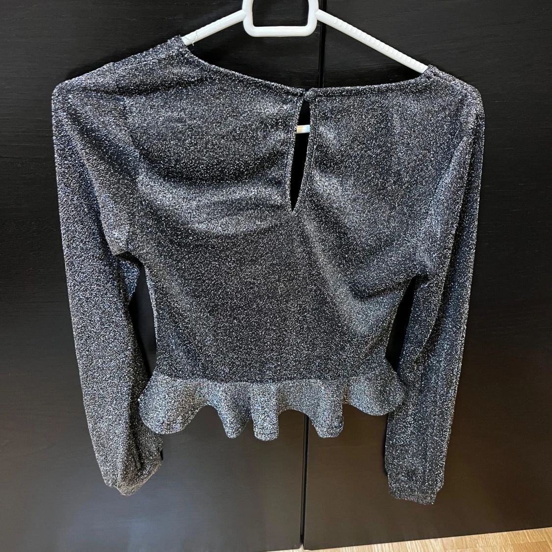 Glittrig svart topp med volang - 1