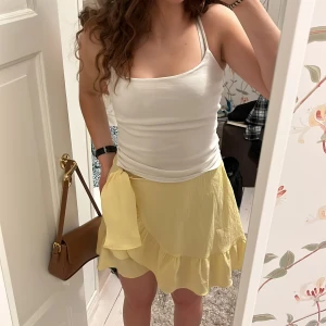 Gul kjol från Vero Moda - Säljer en gul kjol från Vero Moda med volangdetaljer. Kjolen har en omlott-design. Den är gjord i ett lätt och luftigt material.💛
