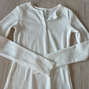 Vit ribbad långärmad topp från Dazy - Säljer en stilren vit ribbad topp från Dazy. Den har långa ärmar och knappar framtill för en enkel men elegant look. Perfekt för lager-på-lager eller som den är. Passar till många olika stilar och tillfällen.🩷🩷