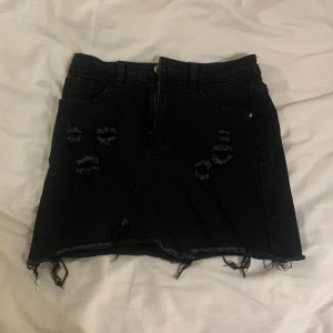 Svart kort jeanskjol  - Snygg svart jeanskjol med slitna detaljer