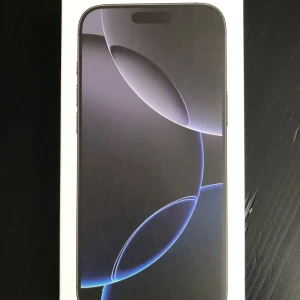 Smartphone i kartong - Säljer en smartphone i originalkartong. Framsidan av kartongen visar en stilren design med en skärm som har en mörk bakgrund och ljusa cirkulära mönster. Perfekt för den som söker en ny mobil med modern estetik.