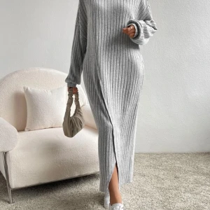 Grå ribbad långklänning - Snygg och bekväm grå ribbad långklänning med slits framtill. Perfekt för en stilren look. Klänningen har långa ärmar och en lös passform som ger en avslappnad känsla. Använd ett par gånger. 