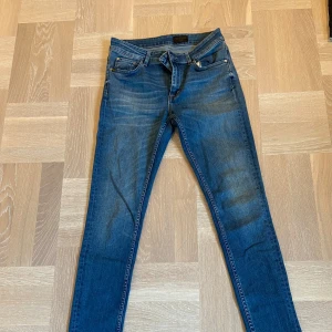 Blå jeans från Tiger of Sweden - Snygga blå jeans från Tiger of Sweden med klassisk femficksdesign och normal passform. De har en midwaist och är tillverkade i ett slitstarkt denimtyg. Perfekta för en stilren look. De är i ett fint skick o sparmsamt använda! Storlek 28/30. Vid frågor eller funderingar/fler bilder är de bara att höra av sig! // leon😊