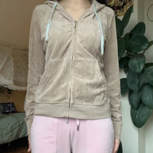 Beige zip-up från Juicy Couture - Säljer en beige zip-up tröja från Juicy Couture med dragkedja och huva. Tröjan har långa ärmar och ett jättefint mönster och detaljer! 🙈Storleken är lite oklar men passar som en S/M på mig : ) (se bild för passform)