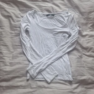 Vit långärmad topp från Bik Bok - Säljer en stilren vit långärmad topp från Bik Bok. Perfekt för lager-på-lager eller att bära som den är. Toppen har en enkel design med rund halsringning. Den har även ett dubbelt lagligt tyg så att det inte ska se genomskinlig ut lite noprig
